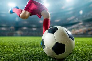 A soccer player kicking a soccer ball in the field