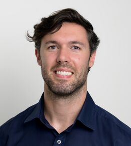 Professional headshot of sports osteopath Jerome Smith smiling and wearing a blue shirt
